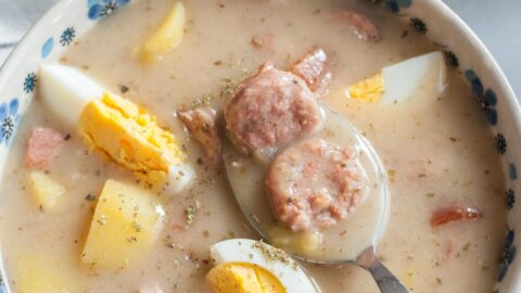 Żurek soup with potatoes and eggs in a white-blue bowl.