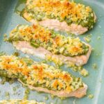 Baked pesto salmon in a green baking dish.