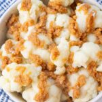 Steamed cauliflower florets topped with crispy fried breadcrumbs in a white bowl.