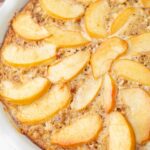 A close up photo of baked peach oatmeal in a white baking dish.